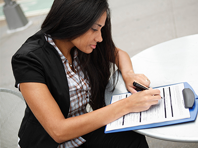 Woman sitting at table filling out application on a clipboard