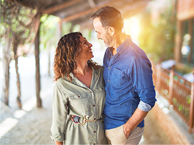 Couple looking at each other lovingly under trellace with sun peaking through the background