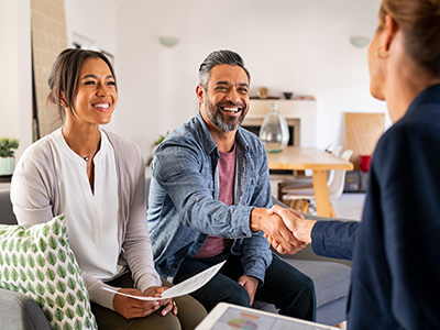 Middle-aged couple meeting with woman in living room and shaking hands