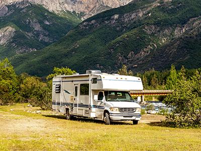RV in field parked next to large mountain landscape