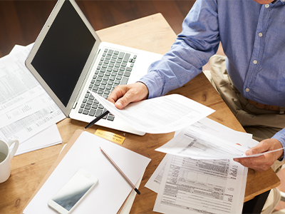 Person sitting at table with laptop looking through documents