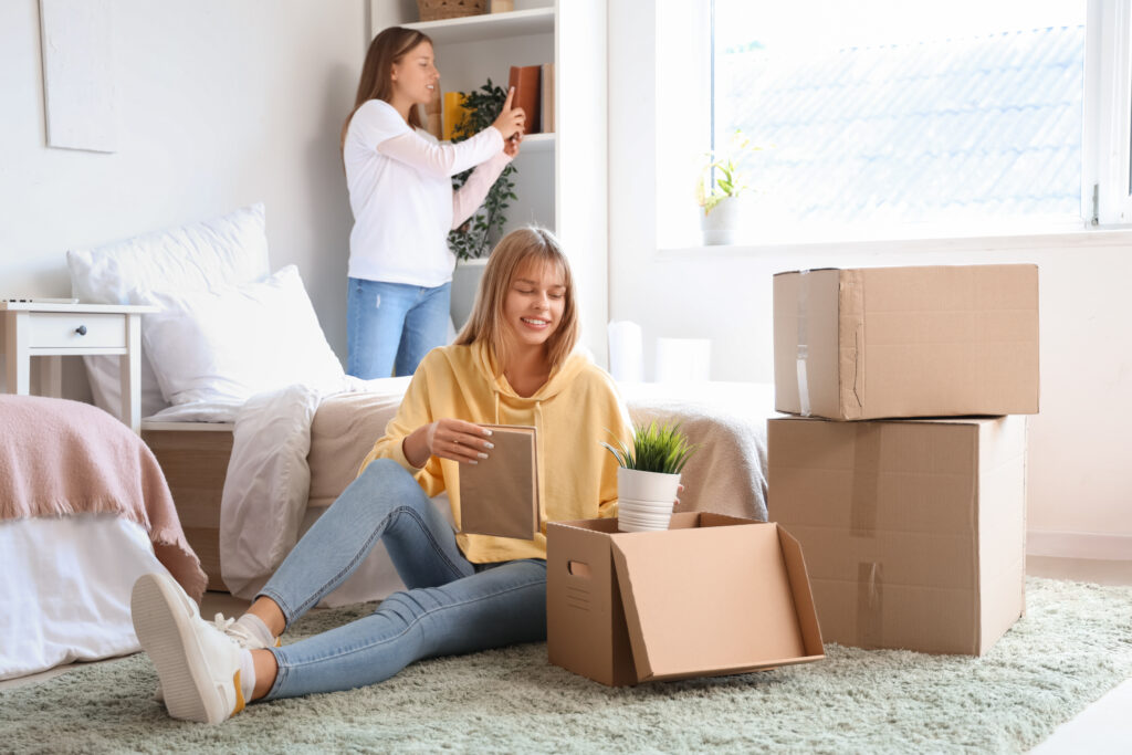 Female student unpacking things in dorm room on moving day